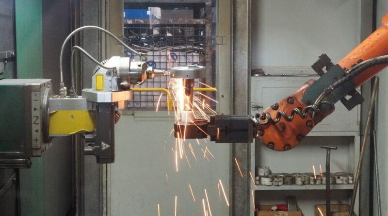 A robotic arm welding in an industrial setting, emitting bright sparks. - Photo by alex on Pexels