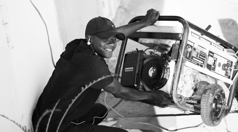 A cheerful young man wearing a cap and earphones operating a portable generator outside. - Photo by Abdulkadir muhammad sani on Pexels